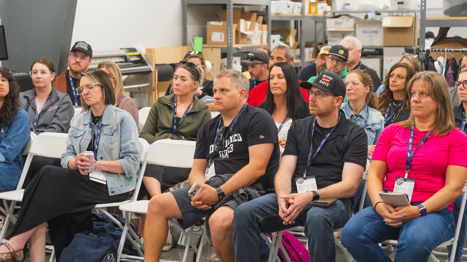 Attendees seated on the Flyover Con shop floor during a session